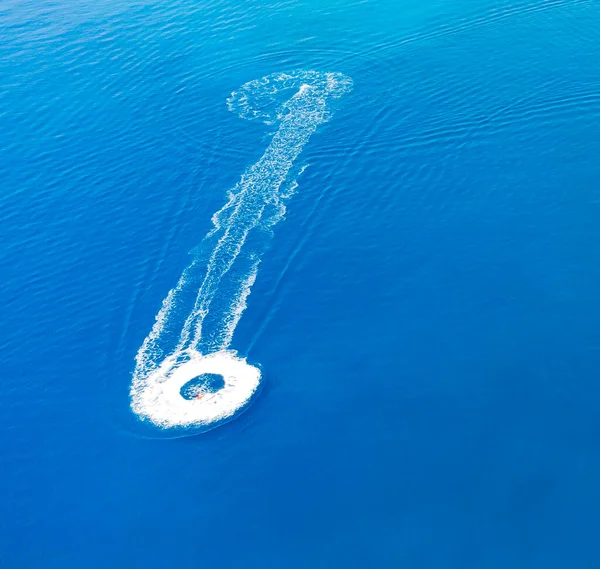 O jet ski viaja a grande velocidade através da água azul, deixando um rastro espumoso. Vista de cima — Fotografia de Stock