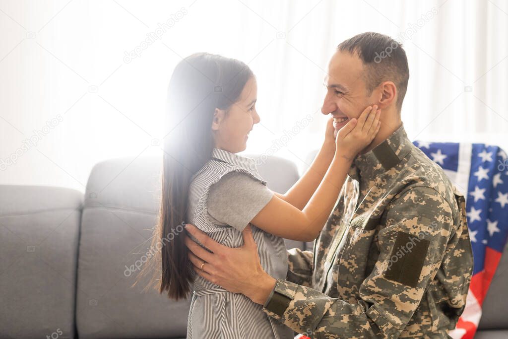 Portrait of happy american family father in military uniform and cute little girl daughter with flag of United States hugging and smiling at camera