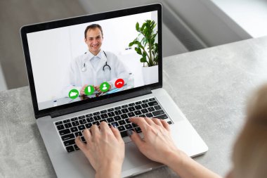 Video konferansında ya da telekonferansta doktor odasında dizüstü bilgisayarla vaka çalışmasını tartışan bir doktor. Webinar 'daki tıbbi ekip yakınlaştırma uygulaması, teletıp, tıbbi teknoloji kullanıyor..