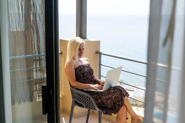 Mulher relaxada em quarto de luxo com computador e vista para o mar — Fotografia de Stock