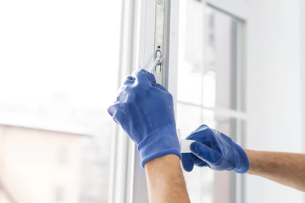 Een arbeider in handschoenen controleert het slot in een nieuwe kunststof deur — Stockfoto