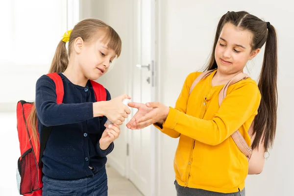 Két iskoláslány kézfertőtlenítőt használ az osztályteremben. — Stock Fotó