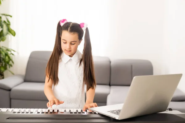 Menina assistindo tutorial aula on-line como aprender um sintetizador — Fotografia de Stock