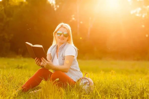 Mot bakgrund av grön äng gräs satt ung, charmig flicka, student läser bok — Stockfoto