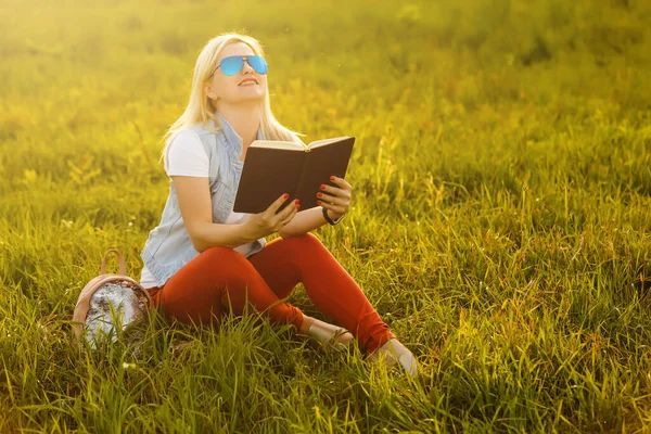 Mot bakgrund av grön äng gräs satt ung, charmig flicka, student läser bok — Stockfoto