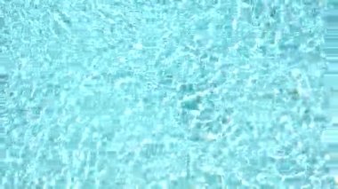 Yüzme havuzundaki saf mavi su, yavaş çekimde ışık yansımaları. Hava görüntüleri.