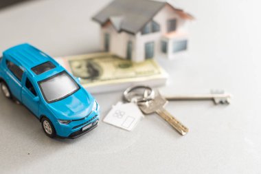 Satılık araba ve ev modeli, parayla birlikte, arka planda anahtar, satılık ev konsepti, yakın plan.
