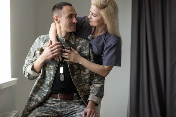 Pielęgniarka opiekuńcza trzymająca za ręce i wspierająca męża wojskowego podczas rozmowy z nim w szpitalu — Zdjęcie stockowe