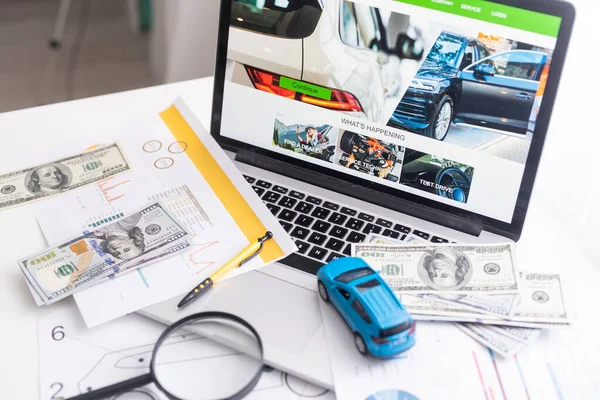 Speelgoedauto met dollars staat op de laptop. De programmeur — Stockfoto