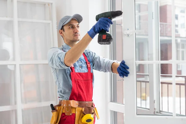 Handyman justera vit pvc plastfönster inomhus. arbetstagare som använder skruvmejsel för att reparera upvc fönster. läxunderhåll. — Stockfoto