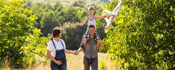 Los padres jóvenes van con el hijo al campo de trigo. El pequeño hijo es feliz cuando es interpretado. — Foto de Stock