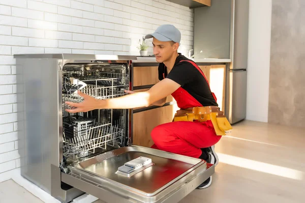 Maestro instalando el lavavajillas en un armario de cocina — Foto de Stock