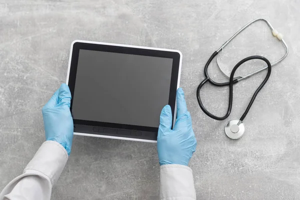 Lékařská ruční tableta s prázdnou obrazovkou a stetoskopem na šedém stole, kopírovací prostor, horní pohled — Stock fotografie