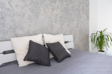 İki yastıklı yatak. Kral yatağında gri çarşaf. Otelde minimalizm