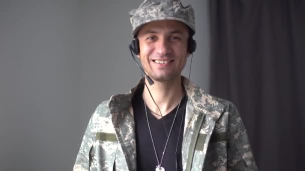 군복을 입고 행복하게 웃고 있는 젊은 남성 군인의 영상 이 가족이나 친구들에게 우주 임무가 끝나고 집으로 돌아가는 기술 전화를 만들고 있습니다.. — 비디오