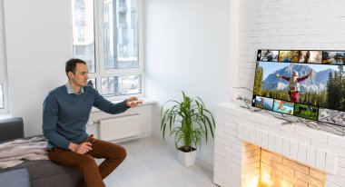 Hafta sonu eğlence aktiviteleri. Milenyum Kafkasyalı uzaktan kumandalı televizyondaki kanalları değiştiren adam. Mutlu genç adam TV 'de ilginç bir program izliyor.