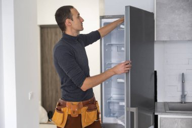 Usta mutfaktaki buzdolabını tamir ediyor.