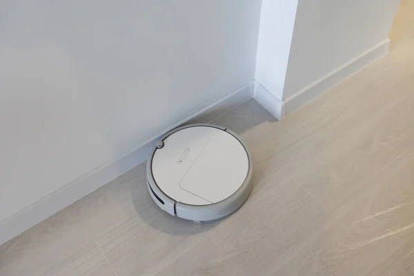 聪明的房子吸尘器机器人在客厅的木地板上运行 — 图库照片