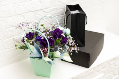 Çiçek demetinde siyah hediye kutusu