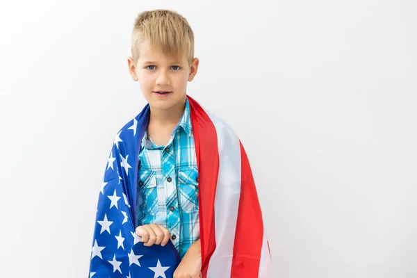 Menino feliz com a bandeira de Estados Unidos enquanto celebra o dia de independência dos EUA no dia 4 de julho com a família. Conceito de férias patrióticas americanas — Fotografia de Stock