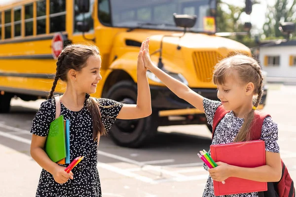 Vzdělání: Usmívající se studenti přátelé připraveni do školy vedle školního autobusu — Stock fotografie