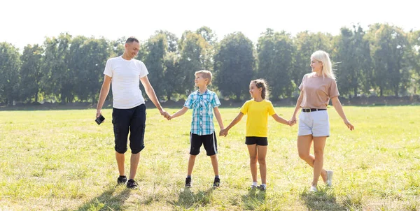 Счастливая семья ходит по полю и держится за руки — стоковое фото