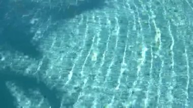 Su yüzeyi dokusu, yavaş çekim temiz yüzme havuzu dalgaları ve dalgalar güneş ışığının yansıması deniz kenarındaki beyaz kum, güneş ışığı arka planı. Su Yakıcı Arkaplan.