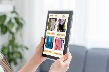 Çevrimiçi mağazada dijital tablette kıyafet arayan kadın