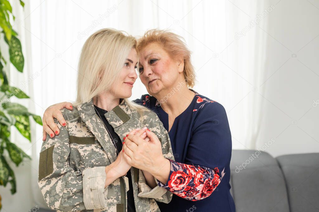 Soldier woman returning home to her family, embracing his mother, close up