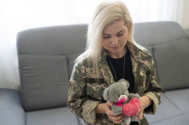 yakın çekim kanepede oturan ve uzağa bakarak TSSB ile askeri üniformalı düşünceli kadın asker portresi