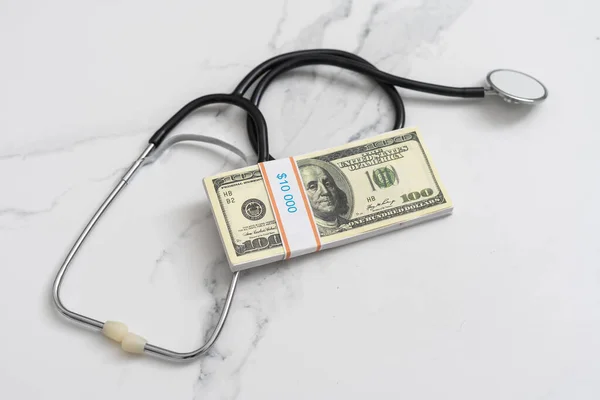 Healthcare, insurance and economy concept: American hundred dollar banknotes with a stethoscope on top of it are lying on black background. Governments covering vaccination against covid-19 pandemic. — Stock Photo, Image