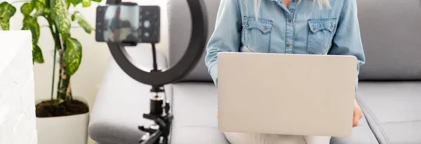 Вид збоку молодої жінки за допомогою смартфона за столом з ноутбуком — стокове фото