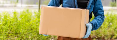Tıbbi maskeli teslimatçı ve eldivenli adam paketi teslim ediyor. Karantina, koronavirüs, izolasyon