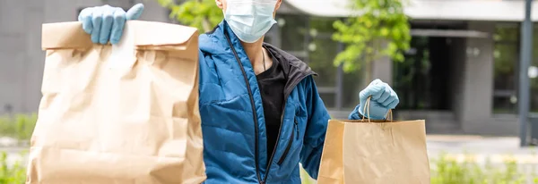 Hispanischer junger Zusteller trägt Mundschutz, während er Paketkasten während des Coronavirus-Ausbruchs trägt. — Stockfoto