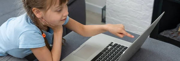 Uczenie się na odległość. Wesoła dziewczynka w słuchawkach za pomocą laptopa studiuje przez system e-learningowy online. — Zdjęcie stockowe