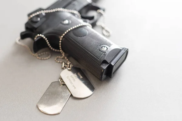 Pistol on table, gun with dog tags — Stock Photo, Image