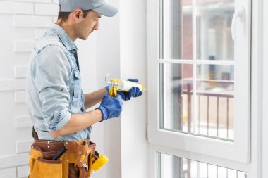 Mühürleme köpük bandı üstünde pencere içinde ev koyarak inşaat işçisi