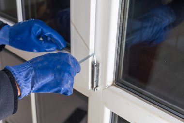 Bir pencere tanıtıcısı yüklemek için bir tornavida kullanarak ve kameraya bakarak yakışıklı adam. Ev rahat ve sıcak yapma