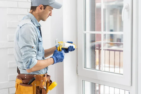 Byggnadsarbetare sätta tätning skumtejp på fönster i hus — Stockfoto