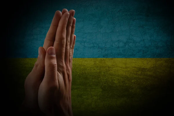 Be för Ukraina. händer be på ukrainska flaggan — Stockfoto