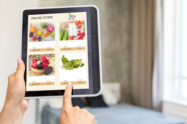 İnternet sitesinden dijital tabletle alışveriş yapan bir kadının arka planı. Kanepedeki bayanın üst görüntüsü. E-ticaret portalından ürün seçerken kızın ekrana dokunuşunun arka görünümü