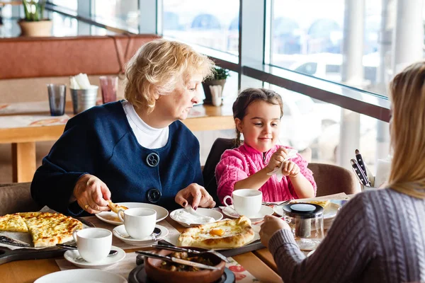 Conceito de infância e pessoas - avó feliz e menina com colher comendo no café ou restaurante ao ar livre — Fotografia de Stock