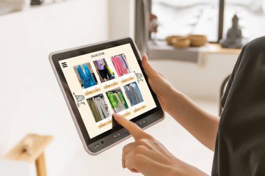 Mutfakta dijital tablet kullanan bir kadın çevrimiçi yiyecek alışverişi yapıyor, tablet ekranda yakın çekim yapıyor. Mobil aygıtlar kullanılarak çevrimiçi satın alma kavramı.