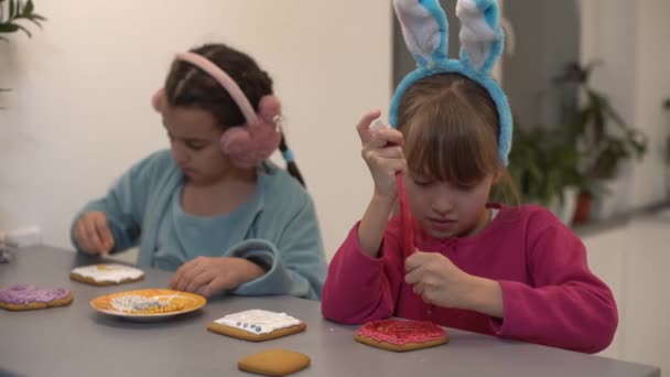 Two little sisters decorating homemade cookies in the kitchen at home. — Stock Video