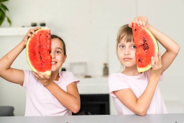 İki çocuk bir dilim karpuz yiyor. Çocuklar dışarıda meyve yer. Çocuklar için sağlıklı atıştırmalık.