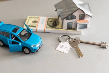 Satılık araba ve ev modeli, parayla birlikte, arka planda anahtar, satılık ev konsepti, yakın plan.