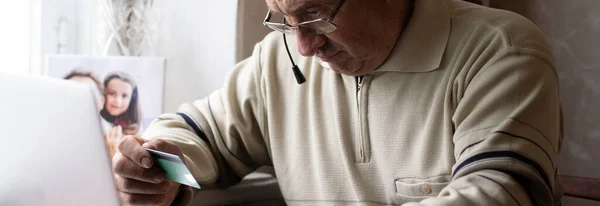 Χαμογελώντας ηλικιωμένος άνδρας φορούν ακουστικά κύμα στην κάμερα έχοντας βιντεοκλήση στο laptop, χαρούμενος ηλικιωμένος άνδρας με ακουστικά κάθονται στον καναπέ στο σπίτι μιλάμε χρησιμοποιώντας σύγχρονες τεχνολογίες και ασύρματη σύνδεση — Φωτογραφία Αρχείου