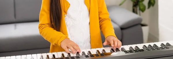조명 실에서 피아노를 치고 있는 아름다운 소녀 — 스톡 사진