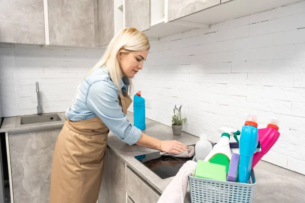 Happy housewife smiling at camera holding rag and spray bottle — Stock Photo, Image