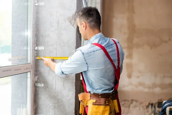 Hombre trabajador montaje ventana en un edificio renovado —  Fotos de Stock